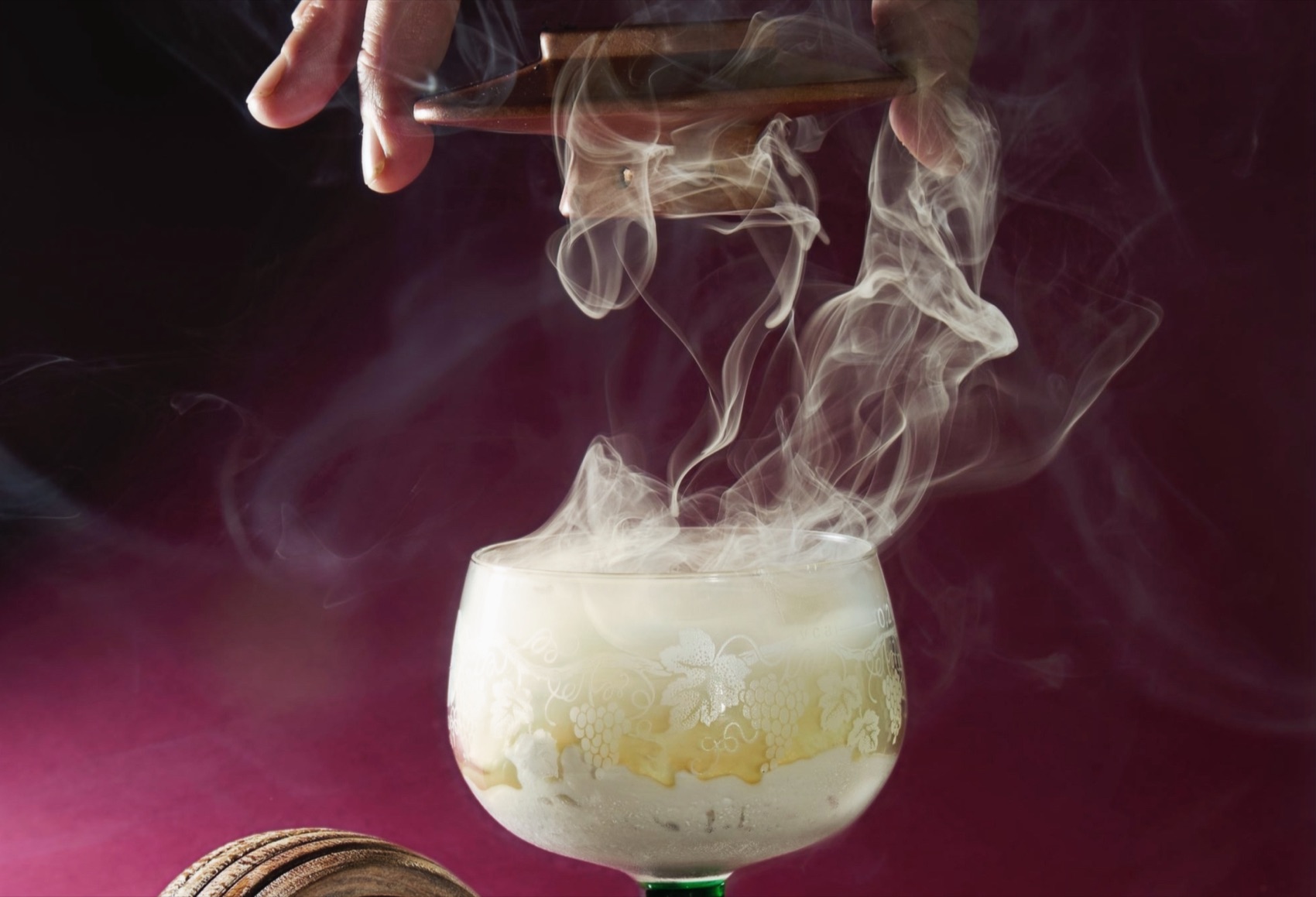 A candlelit infused cocktail, smoke rising